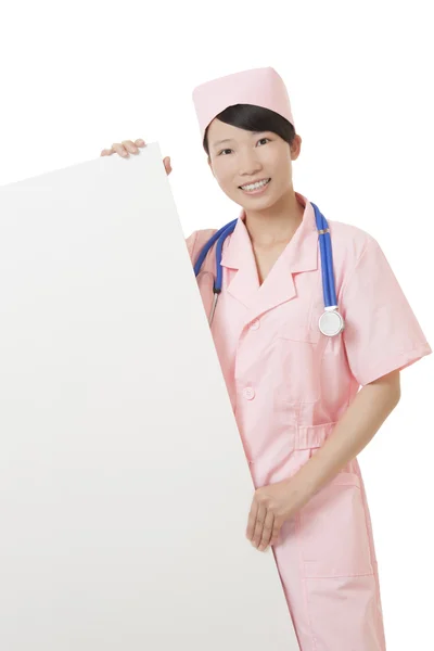 Belle infirmière asiatique tenant un panneau vierge isolé sur un fond blanc — Photo