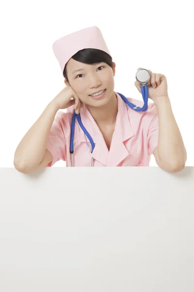 Schöne asiatische Krankenschwester hält ein leeres Zeichen isoliert auf einem weißen Hintergrund — Stockfoto