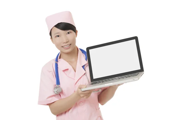 Beautiful Asian nurse holding a laptop computer with a clipping path on the blank screen isolated on a white background — стокове фото