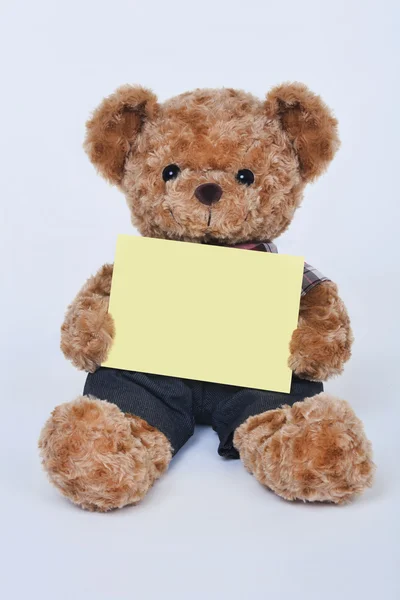A cute teddy bear holding a blank yellow sign isolated on a white background — 스톡 사진
