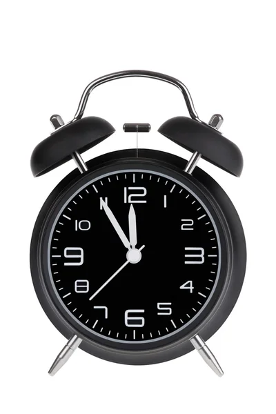 Reloj despertador negro con las manos a 5 minutos hasta las 12. Ilustrando el tiempo se está acabando aislado sobre un fondo blanco — Foto de Stock