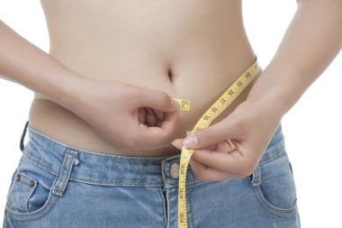 çok uygun bir Asyalı kadın beyaz bir arka plan üzerinde izole beline ölçme