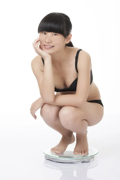 Mulher asiática bonita pesando-se em uma balança e animado com os resultados isolados em um fundo branco — Fotografia de Stock