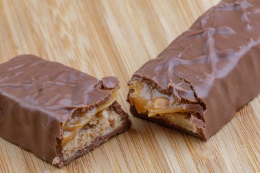 A delicious chocolate and caramel bar isolated on a wooden background