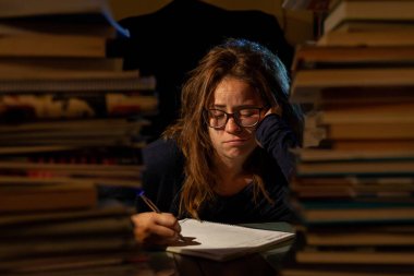 Gözlüklü, güzel, yorgun bir kadın final sınavları için kütüphanede ders çalışıyor..