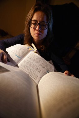 Stresli bir kadın final sınavları için kütüphanede çalışıyor..