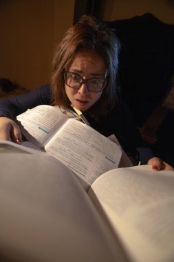 Stresli bir kadın final sınavları için kütüphanede çalışıyor..