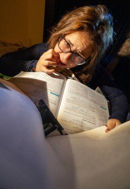 Stresli bir kadın final sınavları için kütüphanede tırnaklarını yiyor..