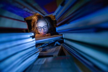 Gece kütüphanede ders çalıştıktan sonra uyuyan yorgun bir kadının fotoğrafını çek.