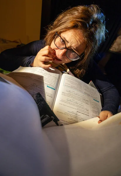 Stresli bir kadın final sınavları için kütüphanede tırnaklarını yiyor..