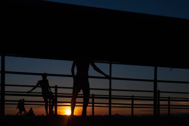 Gün batımında Portekiz 'de bir sahil yolunda futbol oynayan iki gencin silüeti.