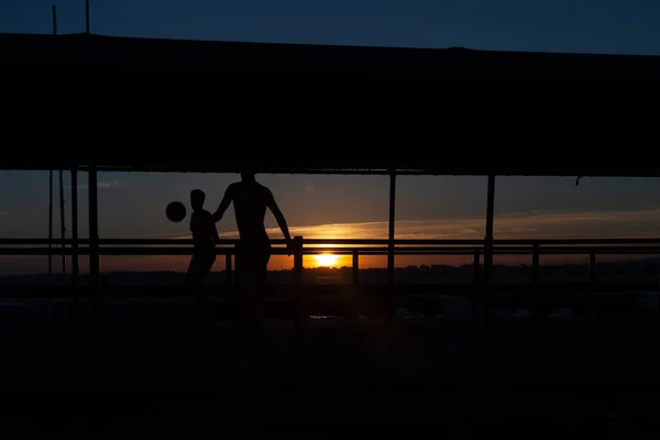 Silueta Dos Jóvenes Jugando Fútbol Una Pasarela Portuaria Una Playa — Foto de Stock