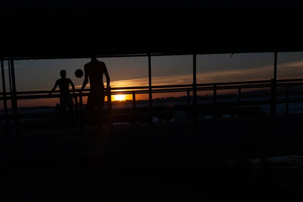 Silueta Dos Jóvenes Jugando Fútbol Una Pasarela Portuaria Una Playa —  Fotos de Stock