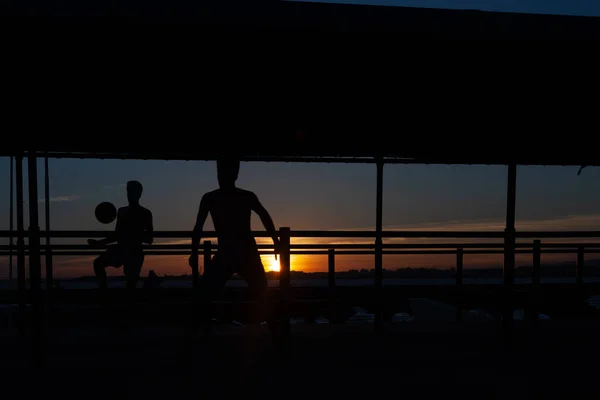 Silueta Dos Jóvenes Jugando Fútbol Una Pasarela Portuaria Una Playa —  Fotos de Stock