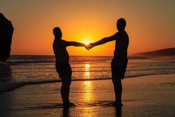 日没時にゲイのカップルがビーチでポーズをとり ロイヤリティフリーのストック写真