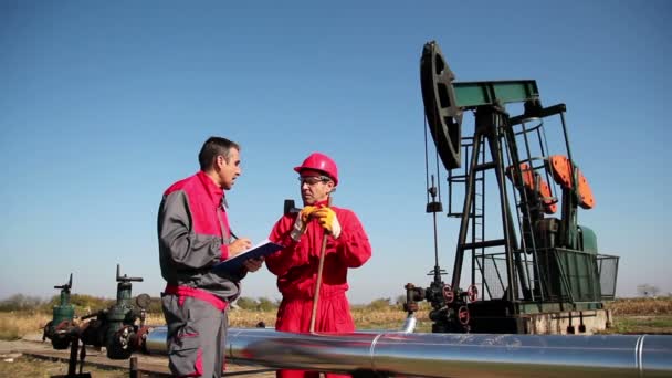 Dos trabajadores frente al pozo petrolero — Vídeo de stock