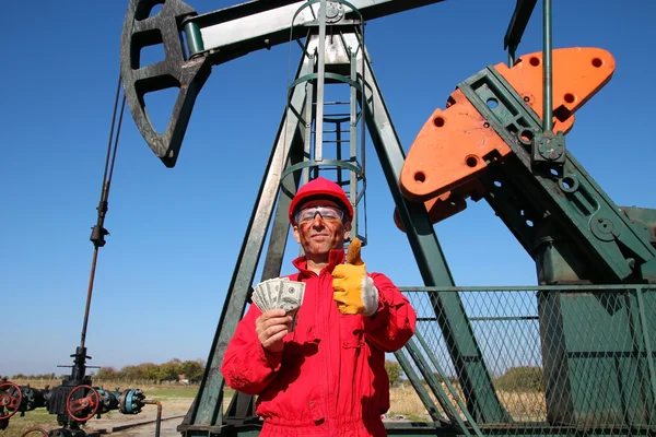 Glad olja då arbetstagaren med pengar och pump jack — Stockfoto