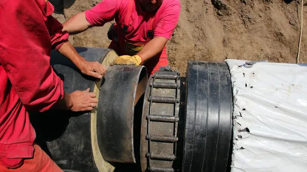 Arbeiter verlegen schwere unterirdische Rohre — Stockfoto