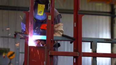 Tren fabrikasında CO2 kaynaklama. Kişisel Koruma Malzemeleri Kaynakçısı. Fabrikadaki erimiş metalin kaynak ve meşalesiyle endüstriyel kaynakçının düşük açılı görüntüsü. 