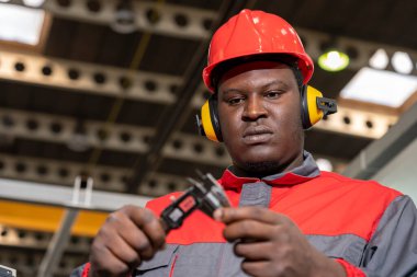 Koruyucu İş Giyimi Afrikalı Amerikalı İşçi Vernier Caliper ile Ölçümleri Kontrol Ediyor. Kırmızı Miğferli Siyah Endüstriyel İşçi Portresi Koruyucular ve İş Üniforması.