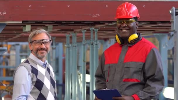 Trabajador Negro Sonriente Ropa Trabajo Protectora Gerente Producción Caucásica Abandonando — Vídeo de stock