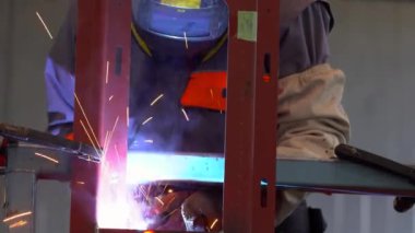 Tren fabrikasında CO2 kaynaklama - Kişisel koruma ekipmanında kaynakçı - Uzaklaştırma. Fabrikadaki erimiş metalin kaynak ve meşalesiyle endüstriyel kaynakçının düşük açılı görüntüsü.