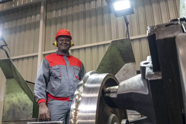 微笑非裔美国人数控机床操作员监控火车车轮制造过程 红头盔 听觉保护器和工作服中的黑人机械师的画像 — 图库照片