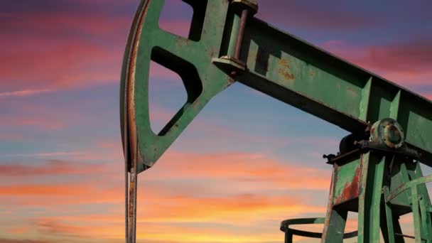 油泵杰克在日落时提取原油 化石燃料能源 石油工业设备 工作台上方云彩飘扬的美丽橙色天空 — 图库视频影像