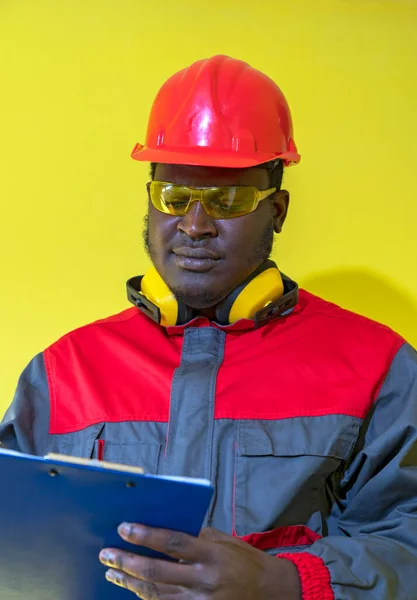 African American Worker Personal Protective Equipment Writing Clipboard Yellow Background — Stock Photo, Image