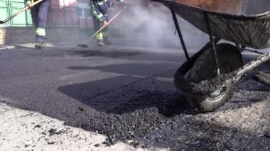 Asfalt Yol Bakımı 'nda çalışan adamlar, Slow Motion Video. Sıcak asfalt yüzeyinden buhar yükseliyor. Yol inşaatında asfalt döşeyen işçiler. Yol Pateni Seviyeli Asfalt.