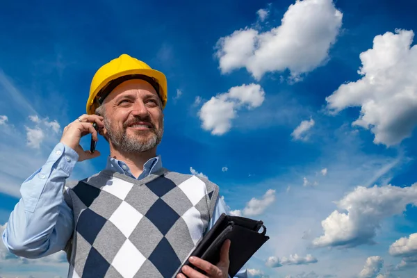Lächelnder Ingenieur Gespräch Mit Dem Handy Vor Blauem Himmel Mit Stockbild