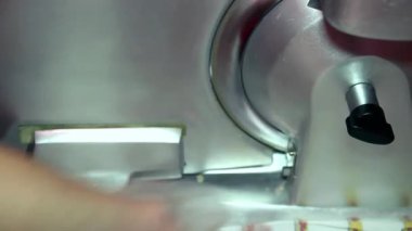 Kadın çalışan süpermarkette et kesmek için elektrikli et dilimleyicisi kullanıyormuş. - Ne? İnsan eli dilimleme makinesinde bir parça jambon dilimliyor..