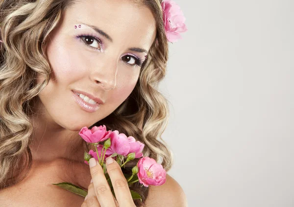 Mooi gezicht met roze rozen — Stockfoto