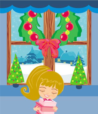 Mutlu küçük kız Noel Baba 'dan bir hediye taşıyor.