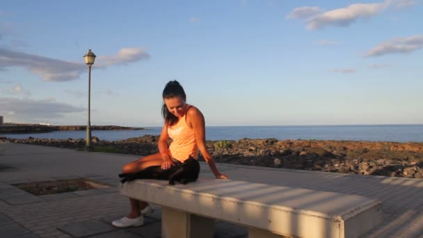 Girl stroking a black cat on ocean landscape — Stock Video