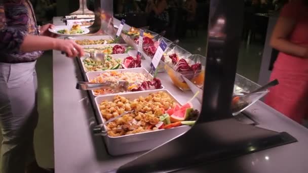 Vrouw die sommige salade bij een buffet — Stockvideo
