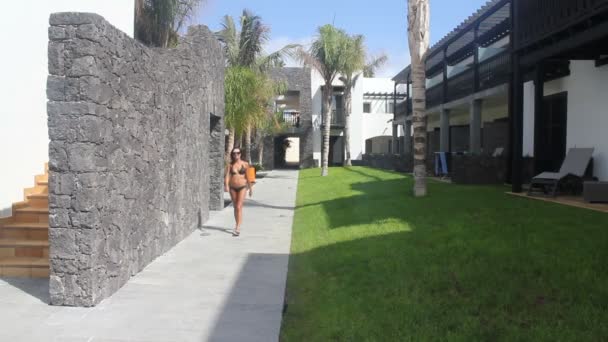 Kvinna i bikini promenader i en exotisk anläggning — Stockvideo