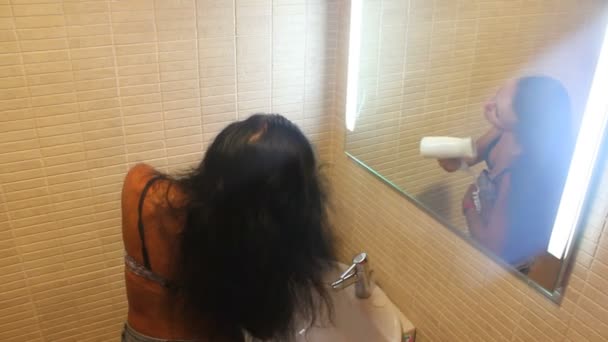 Красивая женщина сушит волосы феном в ванной комнате — стоковое видео