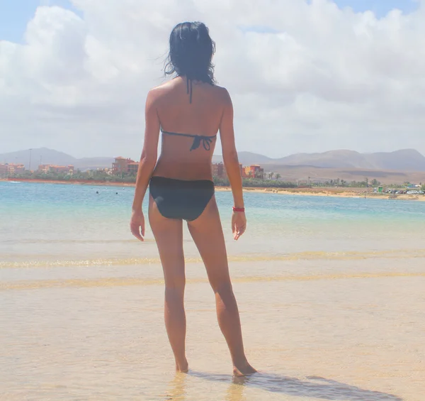Засмагла жінка спиною розслабляється на піщаному пляжі — стокове фото
