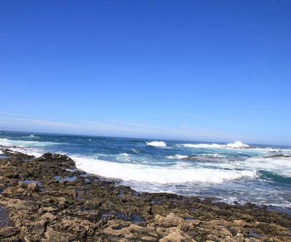 Турбулентные океанские волны с белой пеной бьют прибрежные камни, Фуэрт — стоковое фото