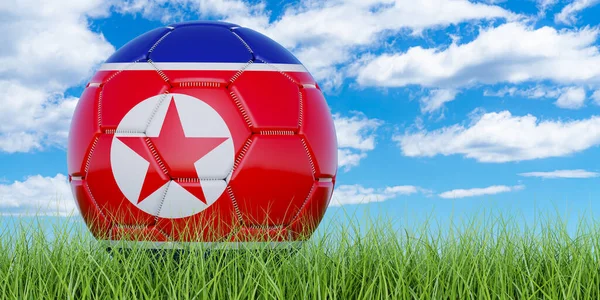 Soccer ball with North Korean flag on the green grass against blue sky, 3D rendering