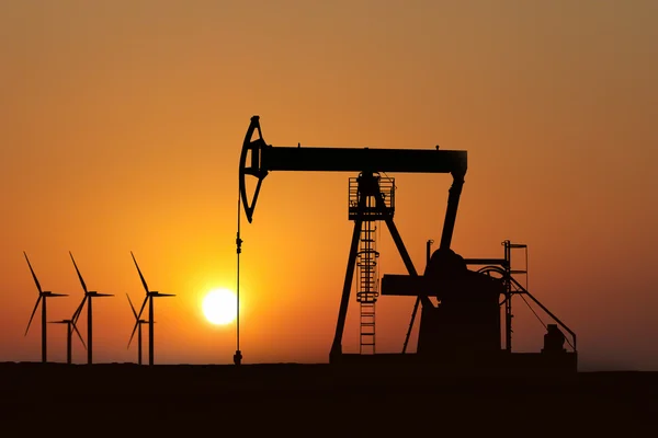 Olie pomp silhouet in zonsondergang en alternatieve energie — Stockfoto