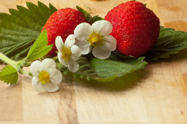 Erdbeere auf Blättern mit Blüten im Vordergrund — Stockfoto