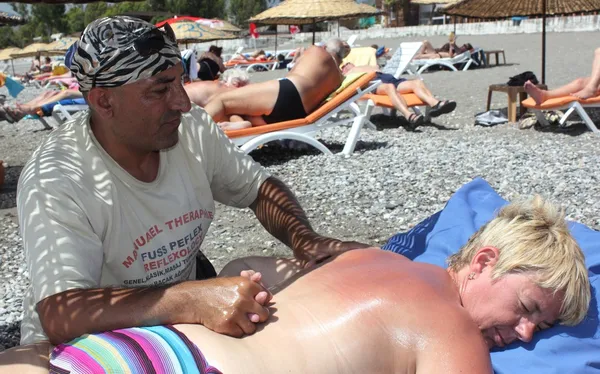 Masseur giving a full massage to a beautiful woman on the beach — Stock Photo, Image