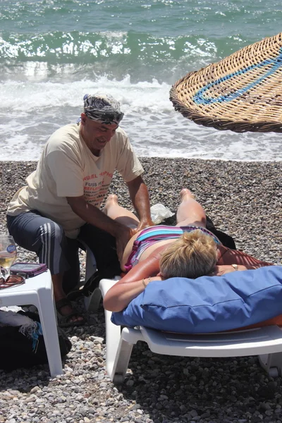 Masseur geven een volledige massage aan een mooie vrouw op het strand — Stockfoto