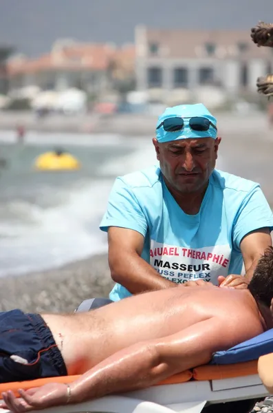 Massagista dando uma massagem completa para um macho na praia — Fotografia de Stock