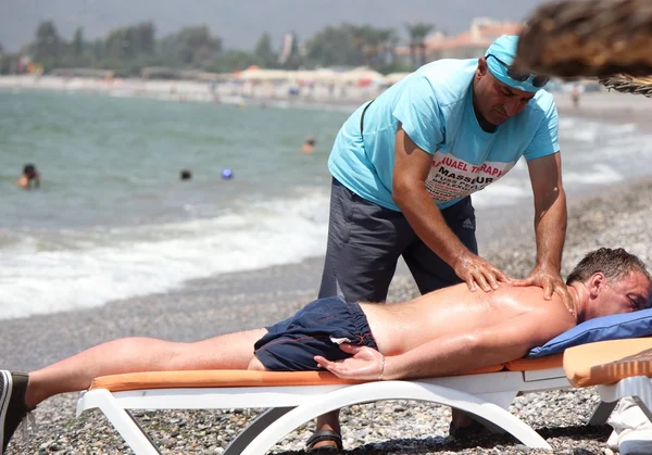 Masseur giving a full massage to an amputee on the beach — Stock Photo, Image