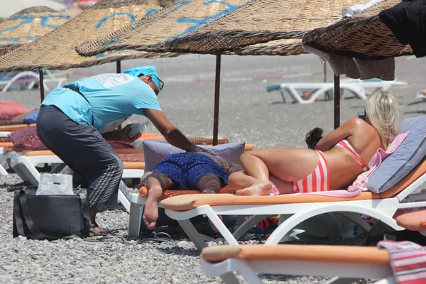 Masseur gibt eine volle Massage am Strand — Stockfoto