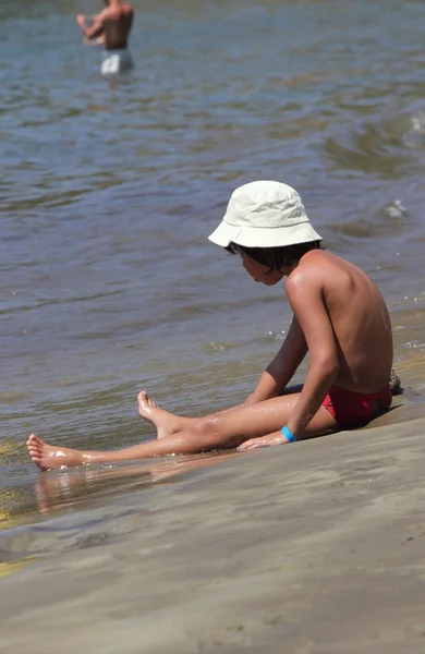 Um menino sentado na beira das águas — Fotografia de Stock