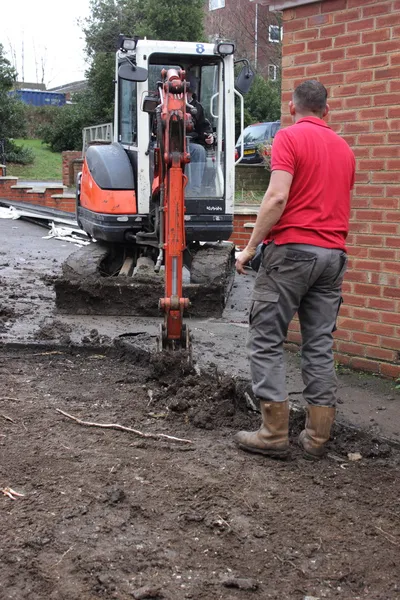 Una mini excavadora excavando un camino de entrada — Foto de Stock